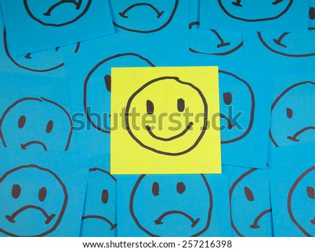 Positive smiley face on sticky note over sad faces