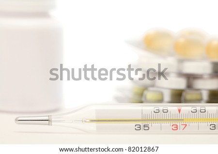 Medical still-life with thermometer and tablets. Temperature is 37.2