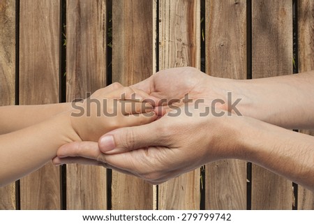 father and son holding hands on wooden wall background