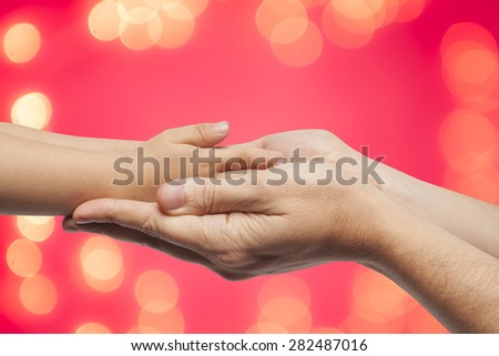 father and son holding hands on red christmas lights background