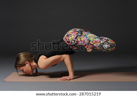 Woman doing yoga in studio on grey background.