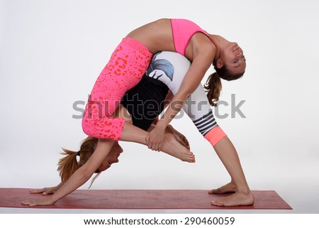 Practicing acro yoga exercises in group. People doing yoga exercises in studio on white background.