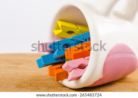 Group colorful pastel of wooden clothespins in coffee cup on wooden board isolated on white background