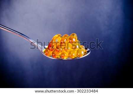 Fish oil on silver spoon with blue background
