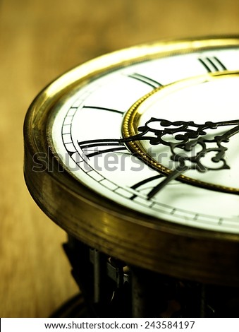 Mechanism of old clock on wooden background. Clock face and hands showing five minutes to midnight.