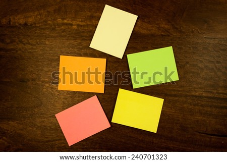 Colorful blank sticky notes lying on a  dark mahogany table. View from the top.