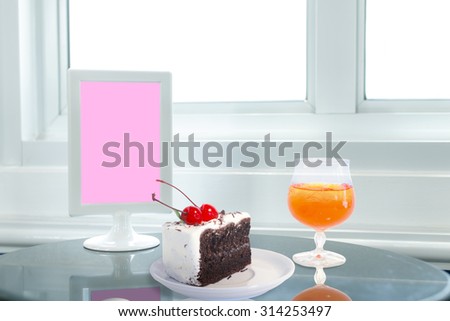 Cherry chocolate cake and Orange juice setting on table.
