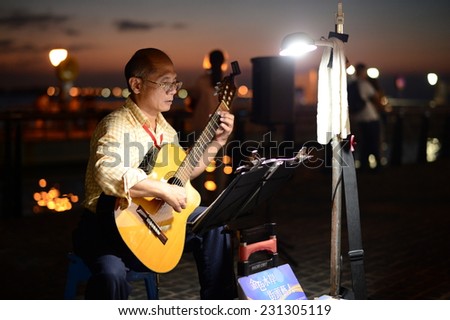 Taipei, Taiwan - 9 Nov, 2014: Unidentified Street Performer who playing classical guitar at riverside of Tamsui in Taipei. It is a destination for tourists to enjoy food and sunset along riverside.