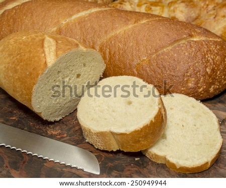 fresh baked yeast bread loaves on a cutting board with a couple of slices cut\