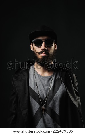 The brutal bearded man in a black fitted hat with cross on chest