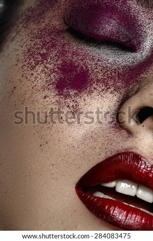 Beautiful female Model with red Lips and purple Makeup on closed Eyes