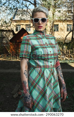 Outdoor retro Portrait of tattooed blonde female Model with green Dress and white Sunglasses