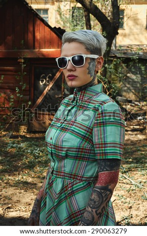 Outdoor vintage Portrait of tattooed blonde young Woman with green Dress and white Sunglasses