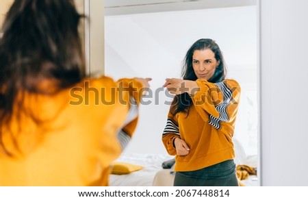 
Self confident single woman pointing finger at her reflection in mirror, dancing and felling good. Independent person with high self esteem talks positive and I can do it motivation.  Imagine de stoc © 