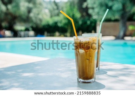 
Summer holiday vacation with frappe refreshment by luxury poolside. Two ice coffee cups with straws behind resort summer pool bar. Greek fredo cappuccino cold drink at beach hotel.  Photo stock © 