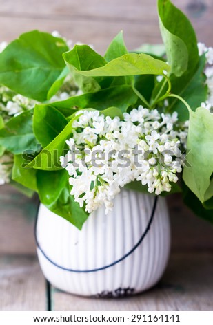 White lilac flowers in the vase on the old wooden table