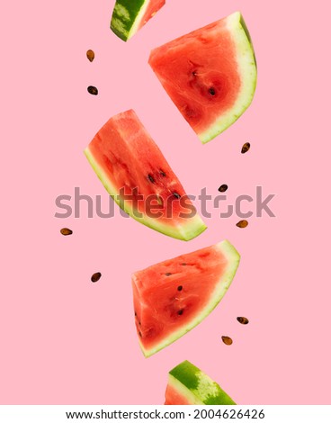 Floating, flying, levitating sliced fresh watermelon on pink background. Summer fruits, berries. Trendy, minimal Creative food. Concept of watermelon day-August 3.