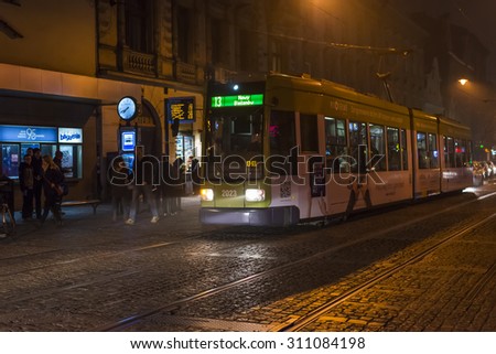 KRAKOW, POLAND - OCT 30, 2014:  Evening tram in the center of the old Krakow. Walking tourists towards the center of the old town. Picture taken in the evening during a trip to Krakow.