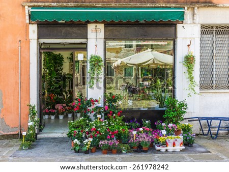 ITALY - JUNE 26; 2014: Windows and doors in an old house decorated with flower pots and flowers
