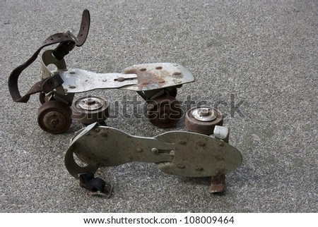 pair of vintage metal roller skates sitting on a cement sidewalk