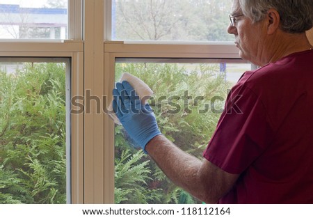 maintenance worker cleaning the windows with a cloth