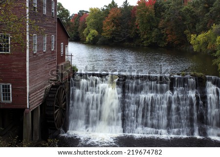 vintage grain mill with water wheel next to a small dam
