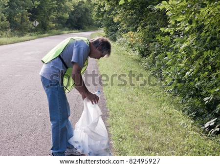 man picking up trash along a rural road