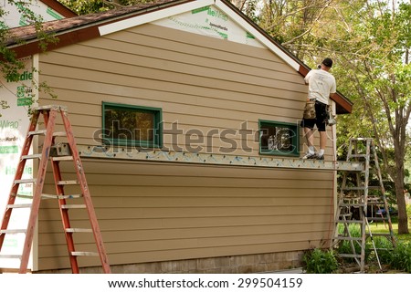 RIVER FALLS,WISCONSIN-JULY 23,2015: A worker installs Hardie Board siding and flashing to an existing structure.