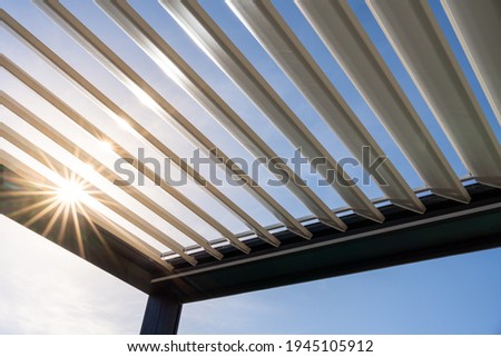 Trendy outdoor patio pergola. the sun's rays pass through the metallic structure