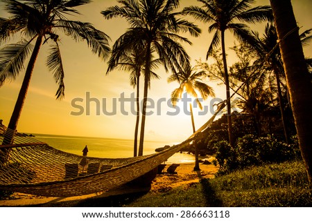 Time to relax with silhouette of hammock and coconut tree at the beach on sunset time in Samui Island Thailand