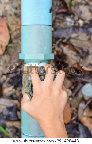 Open a water valve by hand in the garden,Focus on a hand