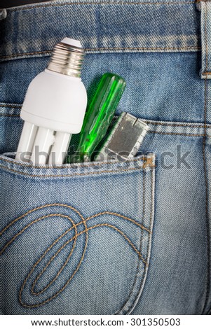Close-up of old screwdriver green and cutter and White Fluorescent Bulbs in Blue Jeans Pocket, electrician.