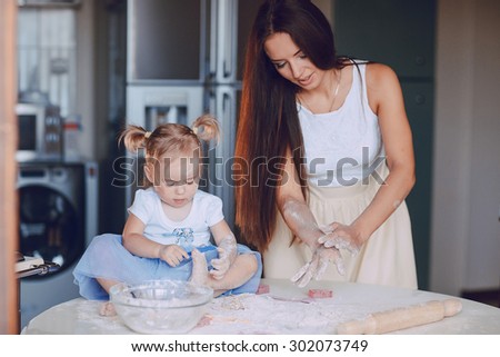 young beautiful mother teaches daughter prepare dough in the kitchen