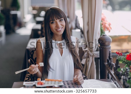beautiful girl enjoying sushi in a cafe on a sunny day