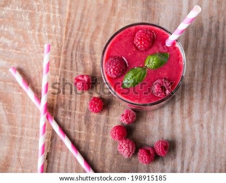 Raspberry smoothie in a glass on wooden table, up view