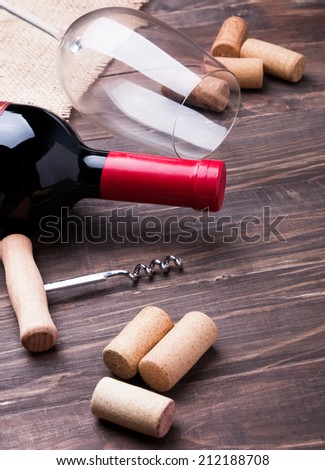 Wine bottle, wine corks, corkscrew and empty glass on the wooden table