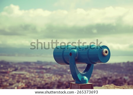 Blue telescope and blurred city on background. Retro toned photo.