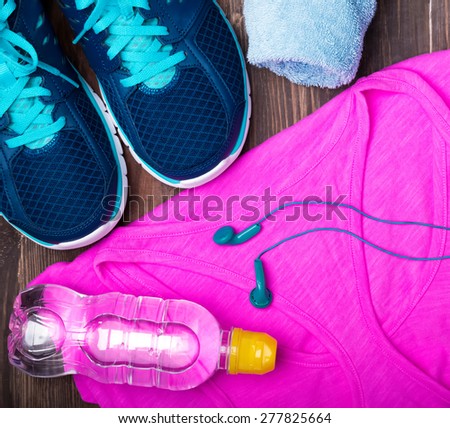Fitness accessories. Sneakers, bottle of water, earphones, towel and sport tank. Top view.