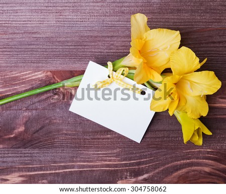Beautiful yellow flower and empty card on te wooden table, top view