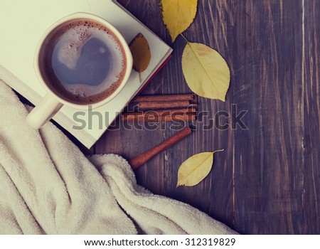 Autumn mood. Cup of coffee, books, blanket and yellow leaves, top view. Toned photo.