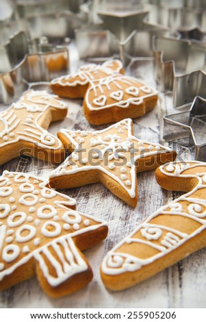 Icing decorated gingerbread cookies with selection of metal cookie cutters on white painted grunge style wooden table