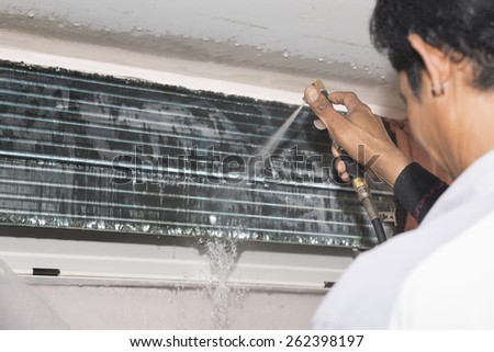 Repairman fixing and cleaning air conditioner unit