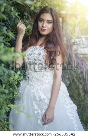 Beautiful elegant asian bride in a summer park.