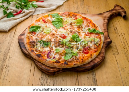 Italian pizza Margherita with greens on wooden table