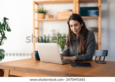 Pensive adult woman making decorative envelopes for selling whil