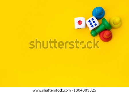 Colorful game chips and two dice are laid out on a yellow background: entertainment, games at home for the whole family, the concept of Board games. Board game. Table games, space for text