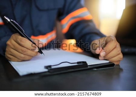An industrial or shipping inspector auditor supervisor in a reflective jacket is writing a pen on a clipboard to check the inventory of tasks that need to be done. Сток-фото © 