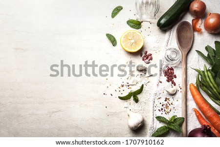 Background image, food-themed, in which the right half presents a composition of vegetables with a wooden ladle and a dish towel, while the left half is left available for any content and announcement