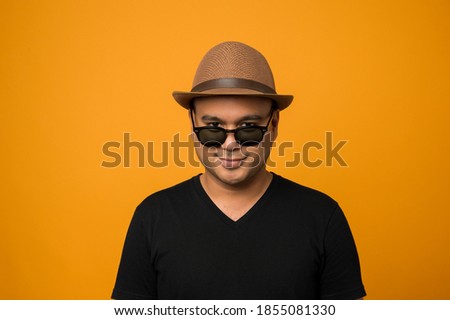 Guy in hat wearing casual clothes put on sunglasses look down at cameraisolated on yellow background Foto stock © 