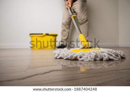 Cleaning workers mopping the wet area. There was spill water on the wooden floor in the living room. Stock fotó © 